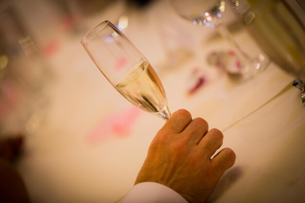 Main coupée d'un homme tenant une flûte à champagne à table