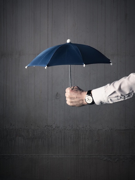 Photo la main coupée d'un homme tenant un parapluie contre le mur