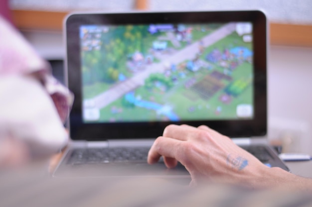 Main coupée d'un homme utilisant un ordinateur portable à la maison