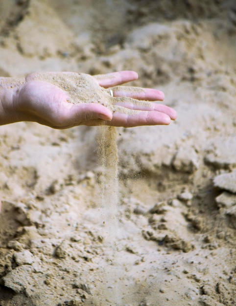 Photo une main coupée jouant avec du sable.