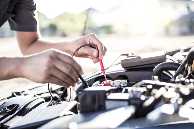 Photo main coupée d'un mécanicien réparant un moteur de voiture dans un atelier