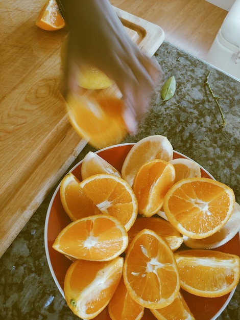 Photo main coupée avec des oranges dans un bol sur la table