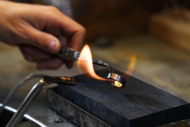 Main coupée d'un ouvrier manuel chauffant un anneau métallique en usine