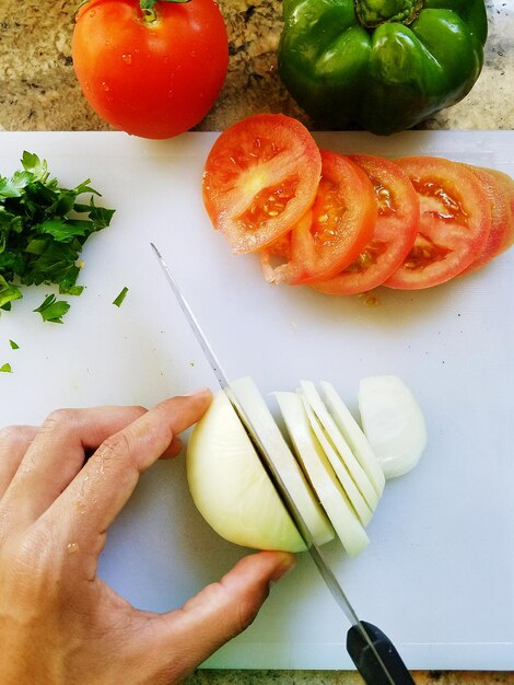 Photo main coupée d'une personne coupant des pommes de terre à bord