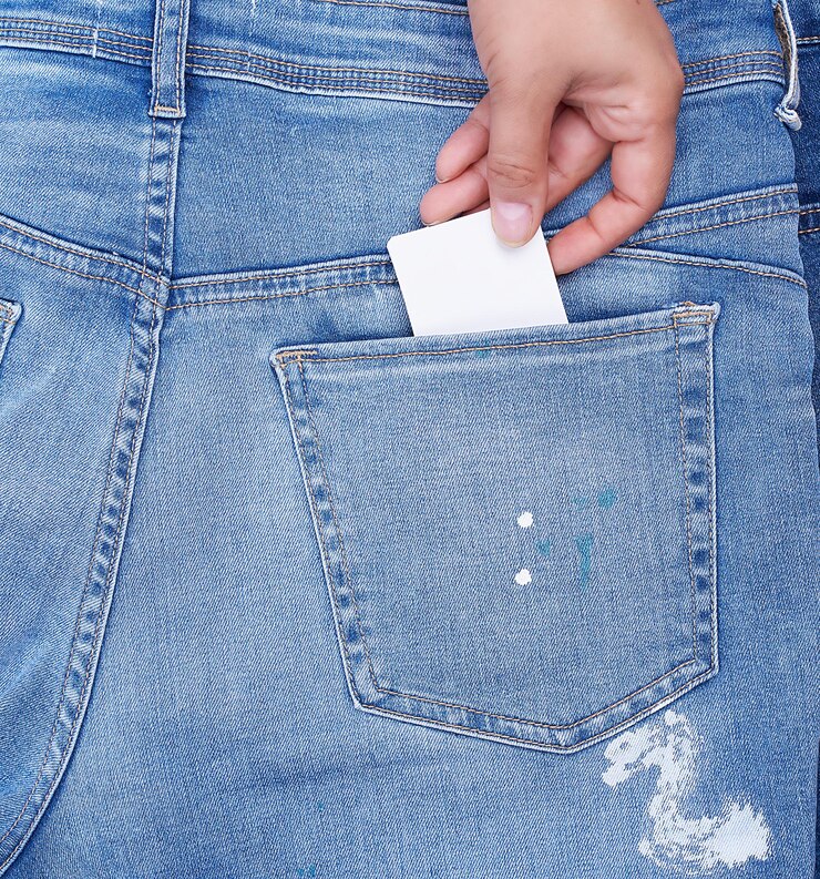 Photo main coupée d'une personne mettant une pancarte dans la poche d'un jean