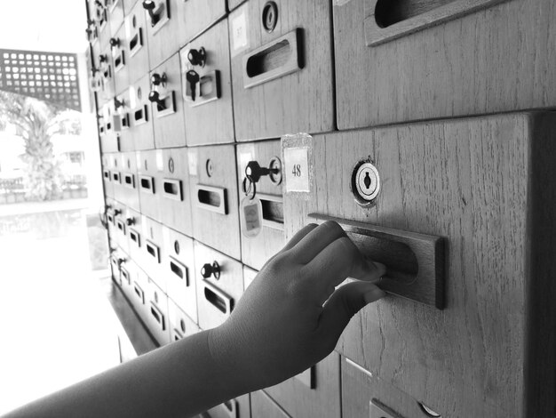 Main coupée d'une personne ouvrant une boîte aux lettres en bois