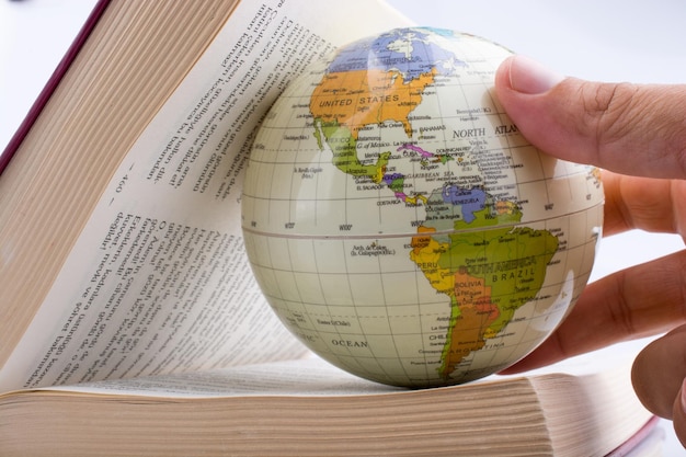 Main coupée d'une personne tenant un globe dans un livre