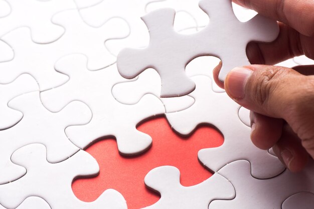 Main coupée d'une personne tenant une pièce de puzzle