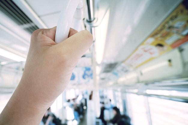 Photo main coupée d'une personne tenant la poignée dans un bus