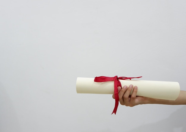 Photo main coupée d'une personne titulaire d'un diplôme sur fond blanc