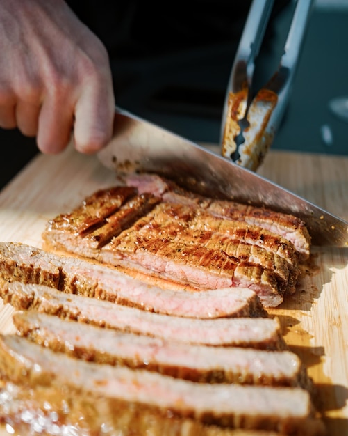 Main coupée d'une personne tranchant de la viande sur la table