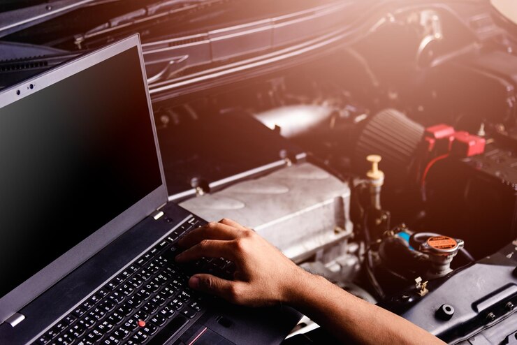 Photo main coupée d'une personne utilisant un ordinateur portable sur le moteur de la voiture