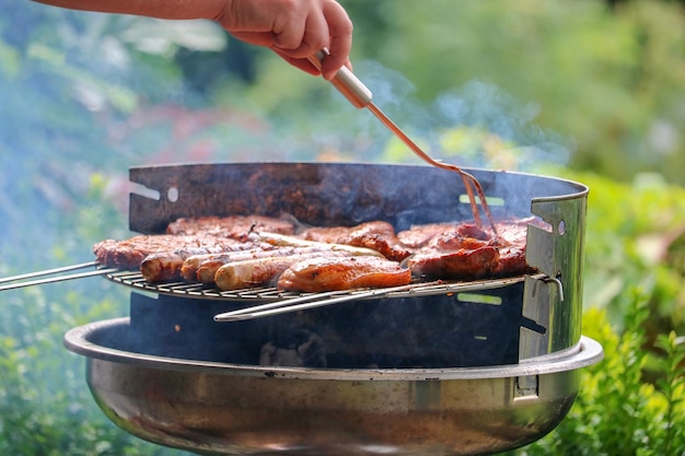 Une main coupée préparant de la viande sur un barbecue