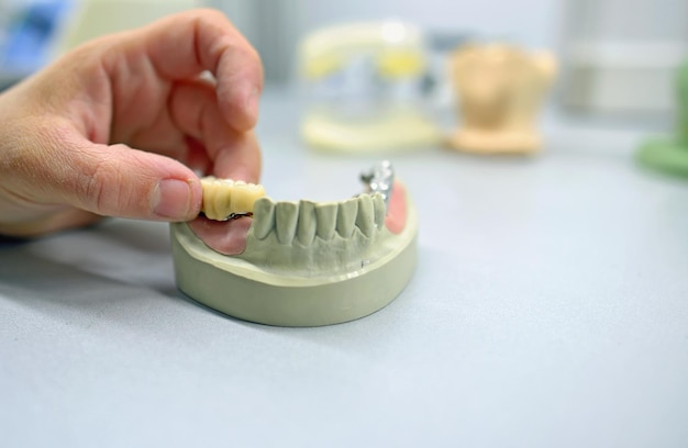 Main coupée d'un technicien dentaire masculin fabriquant des prothèses dentaires en laboratoire