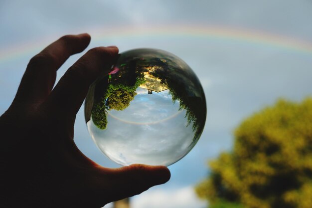 Photo la main coupée tenant une boule de cristal contre le ciel