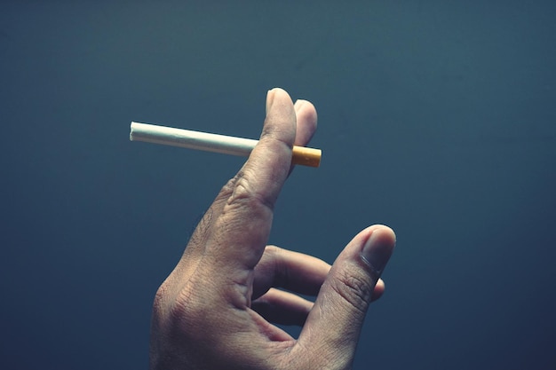Main coupée tenant une cigarette sur un fond gris
