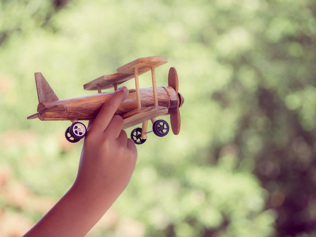 Photo une main coupée tenant un modèle d'avion contre des plantes