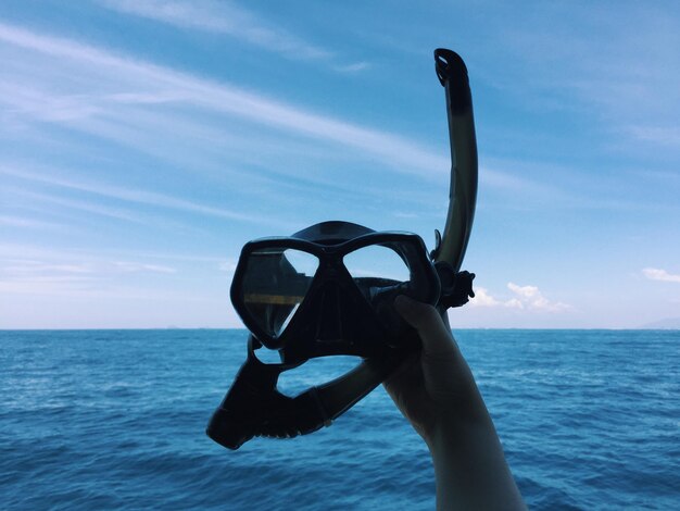 Photo la main coupée tenant un snorkel dans la mer contre le ciel