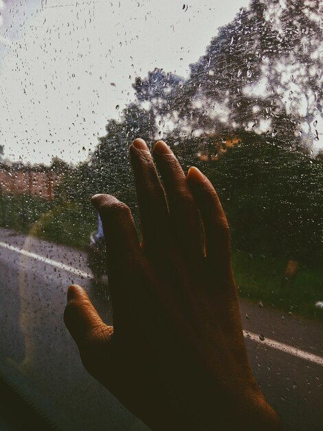 Photo une main coupée touchant une fenêtre mouillée en voyageant dans un bus.