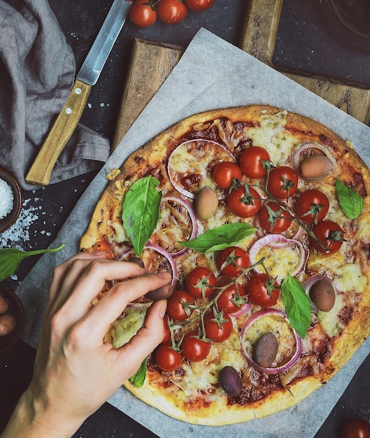 Une main coupée en train de manger de la pizza à la table.