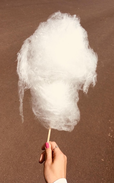 Photo une main coupée en train de prendre du coton sucré sur la plage