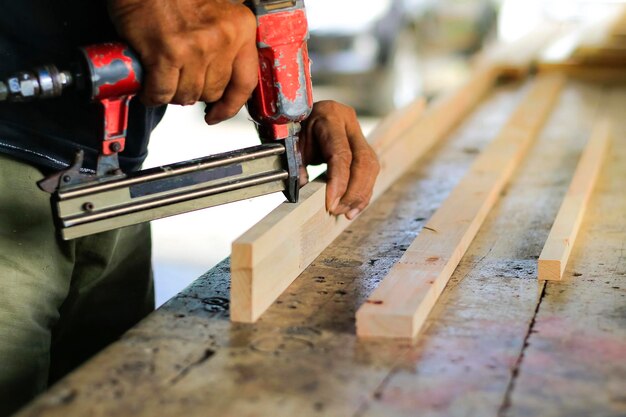 Une main coupée travaillant sur du bois.