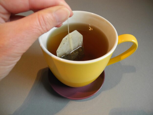 Photo la main coupée trempant un sac de thé dans une tasse à la maison