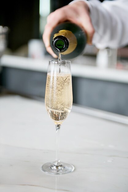 Photo une main coupée versant du champagne dans un verre.