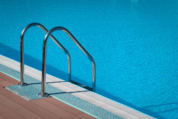 Main courante sur la piscine Piscine avec escalier dans un complexe tropical Piscine d'eau avec reflet ensoleillé Main courante en acier nageant Voyage d'été Entrée à la piscine avec main courante