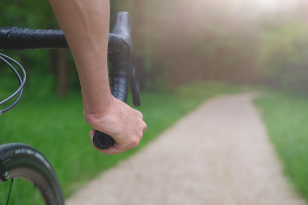 main d'un cycliste sur un guidon de cyclocross dans le contexte d'un chemin dans le parc