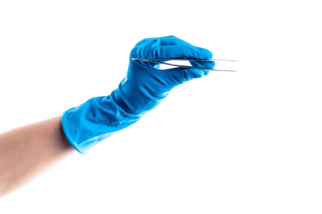 Main dans le gant bleu tenant l'instrument dentaire en métal isolé sur fond blanc