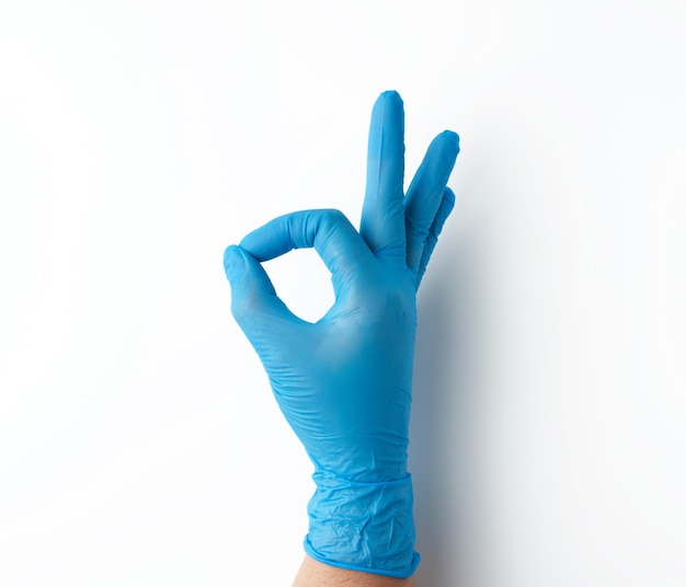Photo la main dans le gant médical bleu montre ok geste fond blanc concept d'approbation