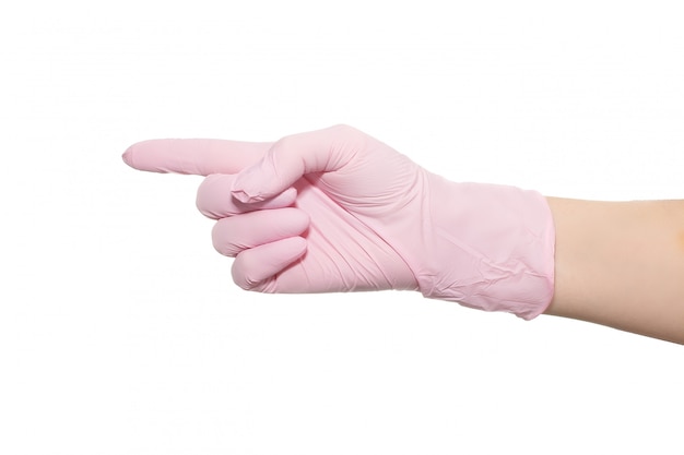 La main dans un gant médical rose sur fond blanc.