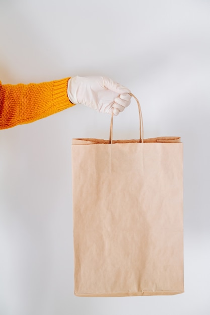 La main dans un gant médical avec un sac de livraison en papier