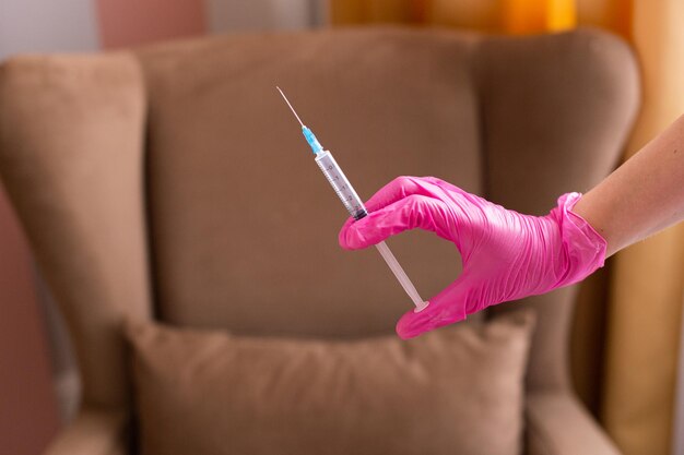 Une main dans un gant médical tient une seringue