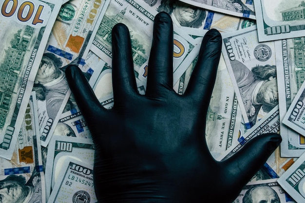 Une main dans un gant noir tient des billets d'un dollar