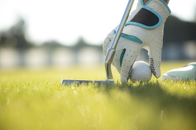 Main dans le gant plaçant la balle de golf sur le tee