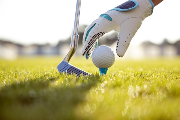 Main dans le gant plaçant la balle de golf sur le tee