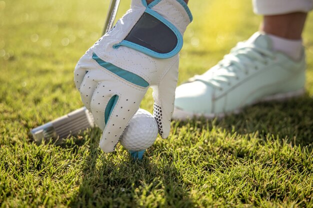 Main dans le gant plaçant la balle de golf sur le tee