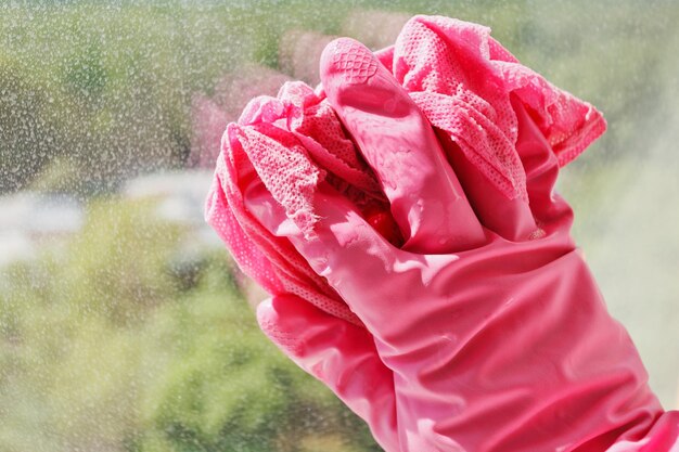 Main dans le gant rose laver la vitre