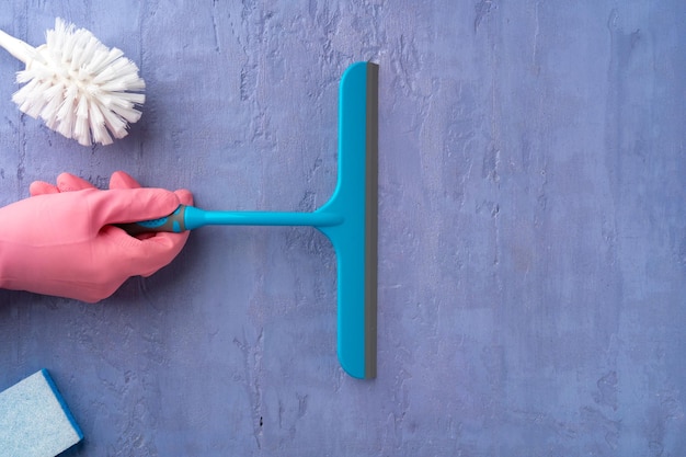 Photo main dans un gant rose tenant une brosse de nettoyage de vitres