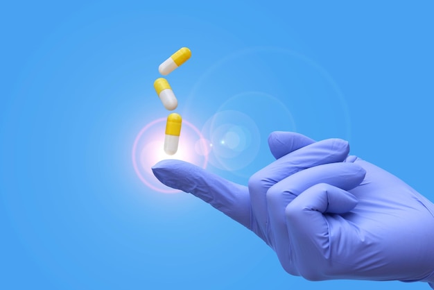 La main dans des gants bleus médicaux contient des capsules de médicaments pour le covid 19