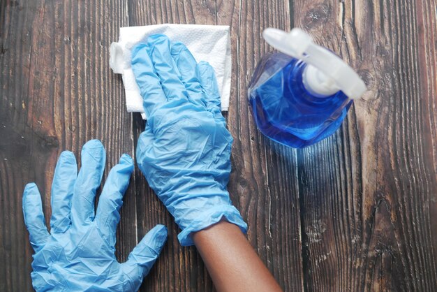 Main dans des gants en caoutchouc bleu tenant une table de nettoyage de flacon pulvérisateur