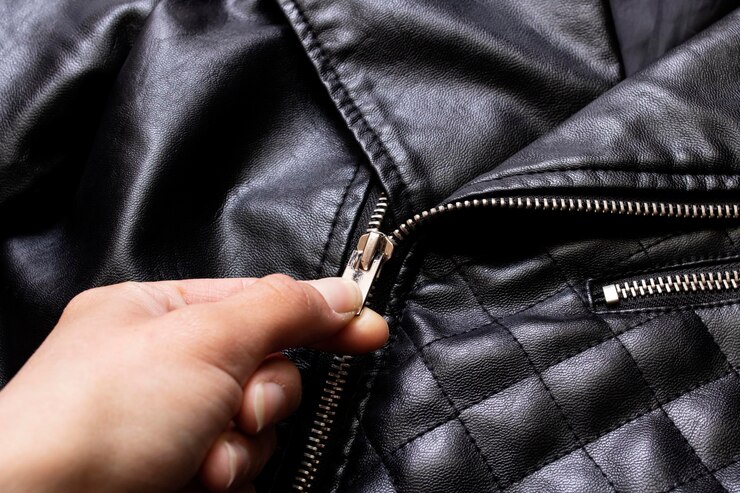 La main déboutonne la serrure de la veste en cuir noire