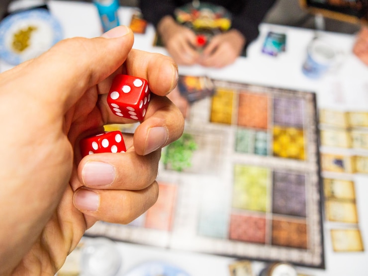 Photo main avec des dés rouges sur le plateau de jeu avec un trois