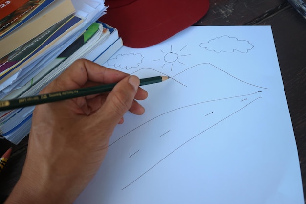 Une main dessinant un paysage avec un crayon