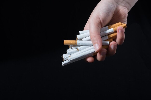 La main donne un paquet de cigarettes sur fond noir