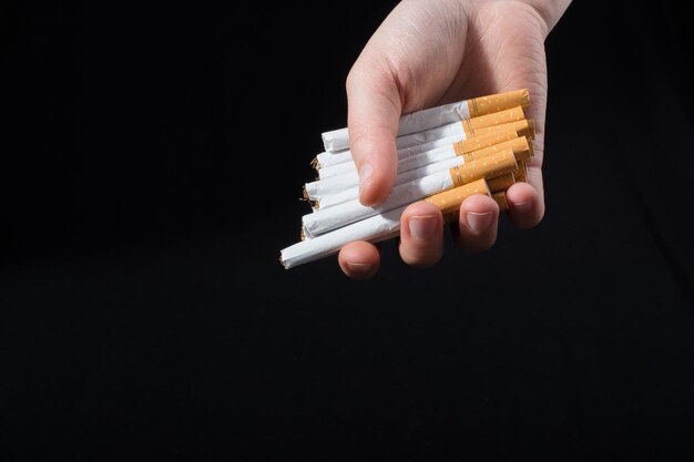 La main donne un paquet de cigarettes sur fond noir