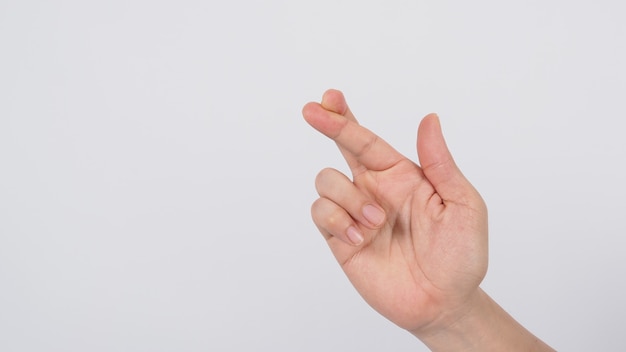 La main droite de l'homme faisant signe de doigts croisés sur fond blanc.