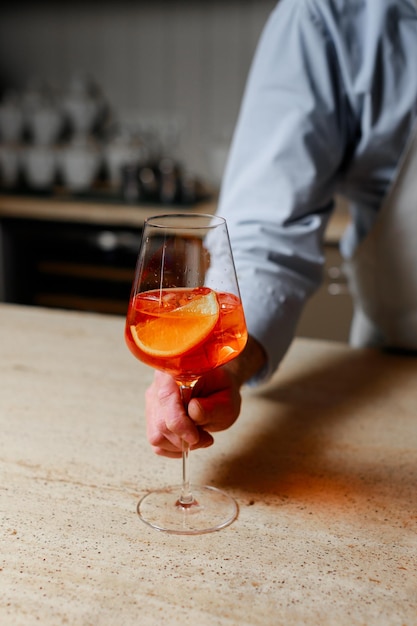 La main du barman avec un verre de cocktail avec gros plan de glace